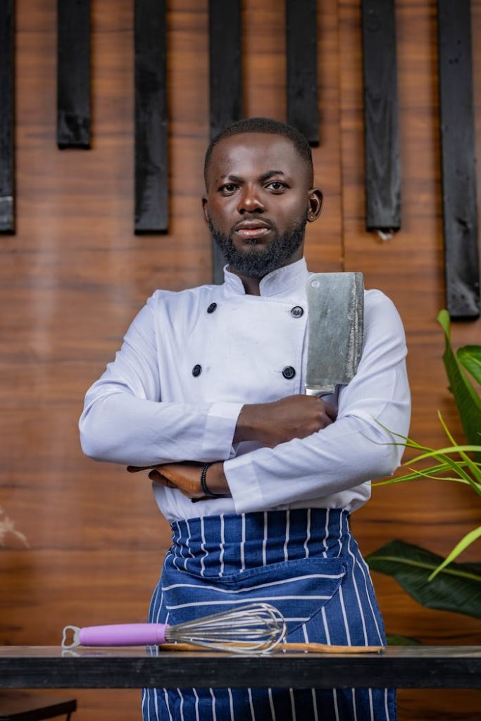 Portrait of a confident chef posing with a cleaver in a stylish kitchen environment.