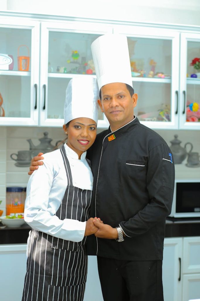 Smiling couple of chefs in a modern kitchen embracing and posing together.