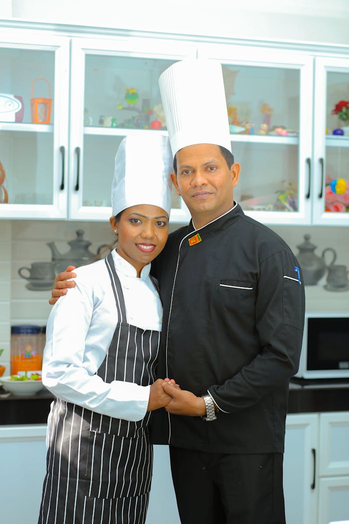 Smiling couple of chefs in a modern kitchen embracing and posing together.